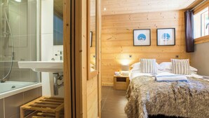 A wooden cabin bedroom with a bed, a nightstand, a lamp, and a framed picture on the wall. - More Mountain - Chalet Jirishanca in central Morzine with Outdoor Jacuzzi. Large split level chalet less than 2 minutes walk to ski lifts & bars. (Morzine)