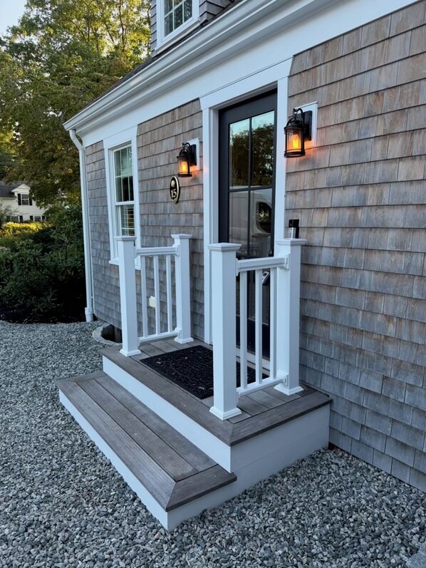 A house with a porch, two windows, and two wall-mounted lanterns.