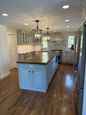 A spacious kitchen with a large island, wooden flooring, and modern appliances.
