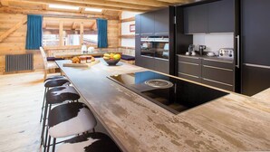 A modern kitchen with a long island, bar stools, and a view of the outside.