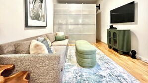 Un salon avec un canapé, un pouf et un meuble.