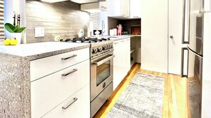 Une cuisine moderne avec des meubles blancs, une cuisinière en acier inoxydable et un réfrigérateur.