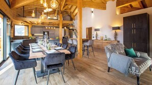 A spacious dining area with a long wooden table, modern chairs, and hanging light fixtures. - Chalet Le Pre hosted by More Mountain Morzine | Luxury 6 Bed 6 Bath Chalet | Sleeps 14. Only 10 min walk into the heart of Morzine with huge outdoor Jacuzzi, large terrace & garden with stunning views of the slopes. Secluded position, yet central. (Morzine)