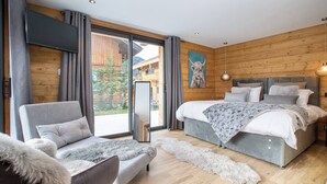 A modern bedroom with a large bed, a sofa, and a mirror. - Chalet Le Pre hosted by More Mountain Morzine | Luxury 6 Bed 6 Bath Chalet | Sleeps 14. Only 10 min walk into the heart of Morzine with huge outdoor Jacuzzi, large terrace & garden with stunning views of the slopes. Secluded position, yet central. (Morzine)