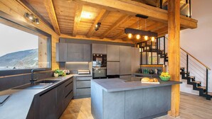A modern kitchen with a central island, built-in appliances, and a wooden ceiling. - Chalet Le Pre hosted by More Mountain Morzine | Luxury 6 Bed 6 Bath Chalet | Sleeps 14. Only 10 min walk into the heart of Morzine with huge outdoor Jacuzzi, large terrace & garden with stunning views of the slopes. Secluded position, yet central. (Morzine)