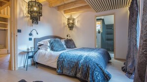 A bedroom with a large bed, a nightstand, a chair, and two hanging lamps. - Chalet Verjus hosted by More Mountain, Morzine | Luxury 5 Bed 5 Bath Chalet | Sleeps 10. Luxury stand alone ski chalet in a very central location with Outdoor Jacuzzi & large terrace. All Mod Cons. Less than 5 mins walk to Ski Lifts. (Morzine)
