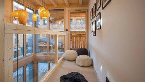 A wooden interior with large windows, woven pendant lights, and a black furry rug. - Chalet Verjus hosted by More Mountain, Morzine | Luxury 5 Bed 5 Bath Chalet | Sleeps 10. Luxury stand alone ski chalet in a very central location with Outdoor Jacuzzi & large terrace. All Mod Cons. Less than 5 mins walk to Ski Lifts. (Morzine)