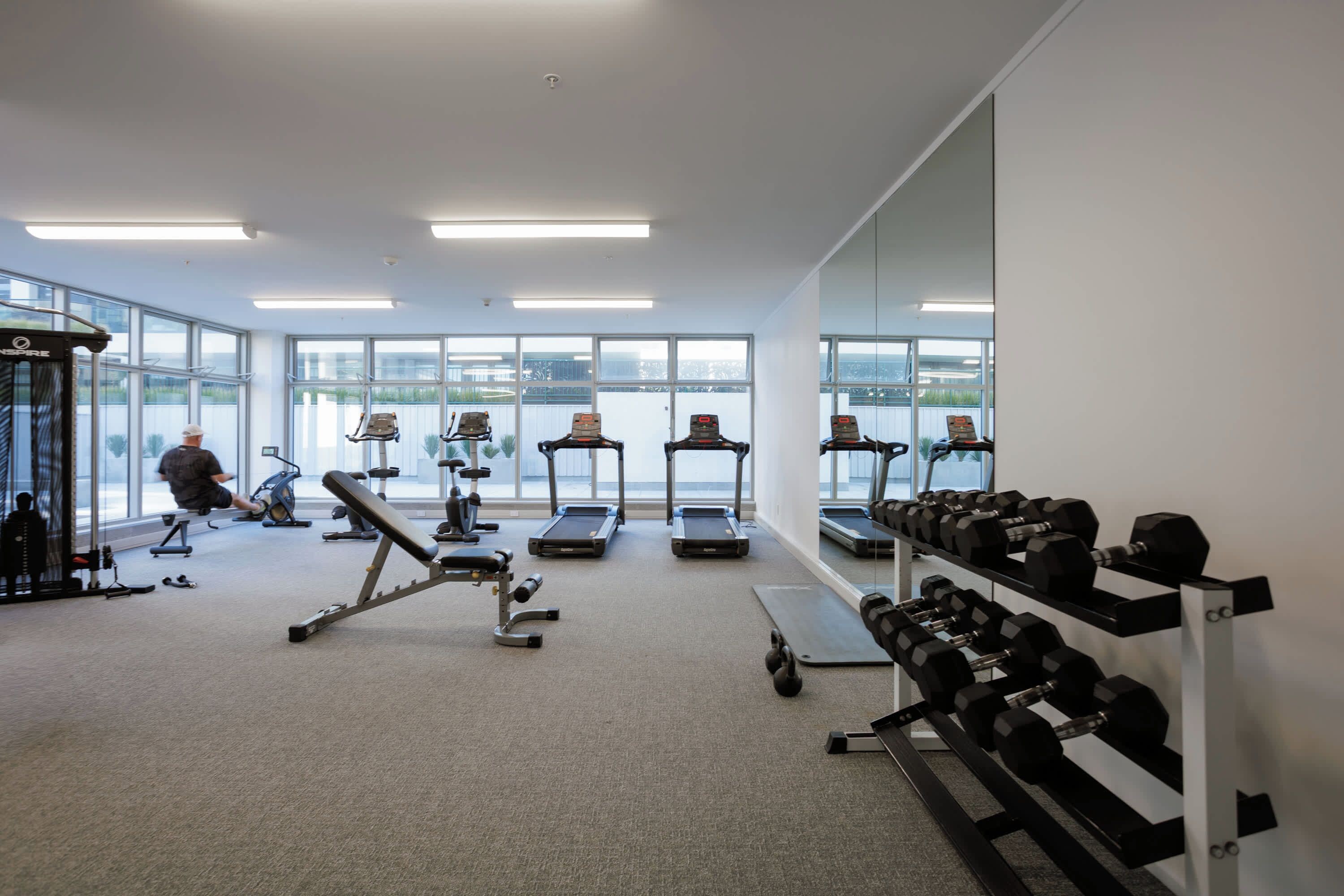 A gym with treadmills, dumbbells, and exercise equipment.