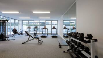 A gym with treadmills, dumbbells, and exercise equipment.