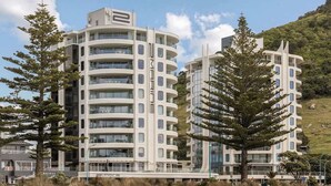 A modern multi-story hotel with a curved facade, large windows, and a flat roof.