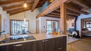 Una cocina moderna con una isla grande, vigas de madera y vistas al exterior.