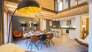 A modern interior with a dining area, kitchen, and a loft space. - Apartment Grand Central hosted by More Mountain, Morzine | Luxury 3 Bed 3 Bath | Sleeps 6. Luxurious and Spacious duplex Penthouse apartment in the centre of Morzine, only 2 minutes walk on the flat to both the Pleney and Super Morzine Telecabines. (Morzine)
