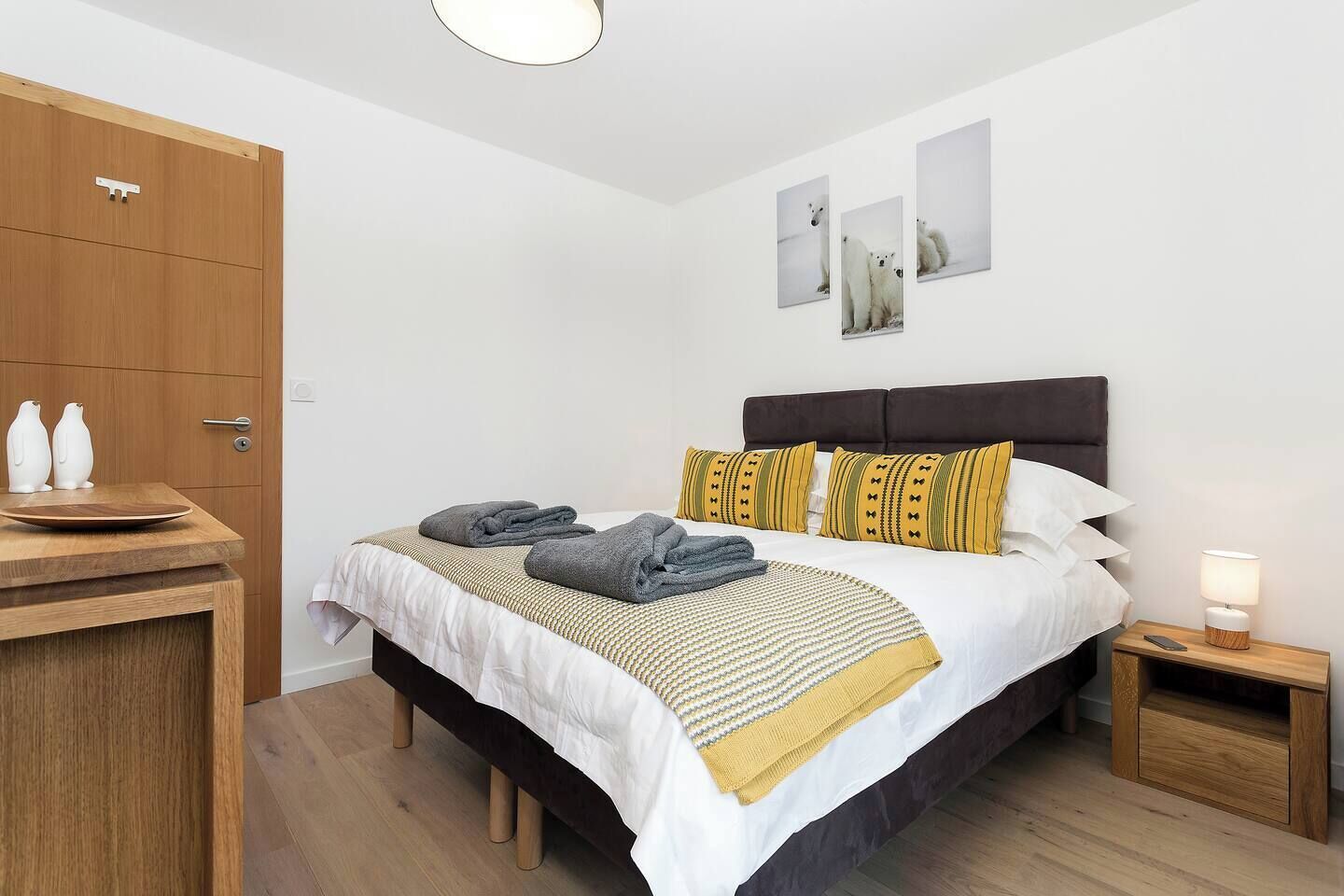 Une chambre d’hôtel avec un lit, des tables de chevet, une armoire et des œuvres d’art accrochées au mur.