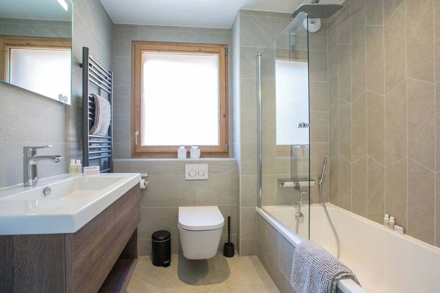 A modern bathroom with a glass-enclosed shower, a white sink, and a toilet.