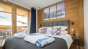 Un dormitorio con una cama grande, un cabecero de madera y vistas a un paisaje nevado a través de una ventana.
