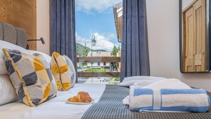 Habitación de hotel con cama, almohadas, manta, toalla y un croissant sobre la cama.