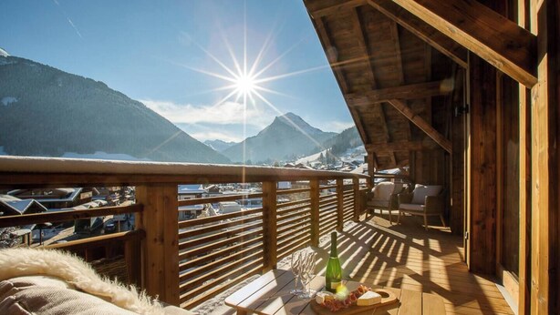 Eine Holzterrasse mit Blick auf schneebedeckte Berge und einen klaren Himmel.