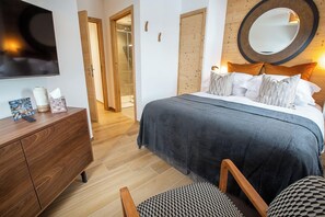 Ein Schlafzimmer mit Bett, Kommode, Spiegel und Fernseher.