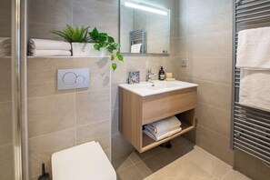 Ein modernes Badezimmer mit einem Holzkosmetikschrank, einem großen Spiegel und einem Handtuchhalter.