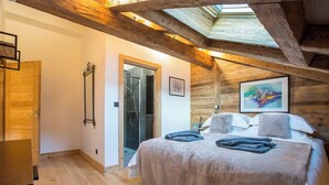 A bedroom with a wooden ceiling, a bed with a white duvet, and a skylight above. - Morzna Etoile hosted by More Mountain Morzine | Luxury 3 Bed 3 Bath | Sleeps 6 | Stylish Split level duplex apartment in a newly renovated farmhouse, just 2 mins from Morzine centre. Terrace with views and Outdoor Jacuzzi. (Morzine)
