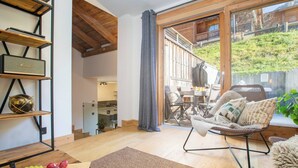 A cozy living room with a wooden floor, a sofa, a coffee table, and a bookshelf with a globe and a Marshall speaker. - Morzna Etoile hosted by More Mountain Morzine | Luxury 3 Bed 3 Bath | Sleeps 6 | Stylish Split level duplex apartment in a newly renovated farmhouse, just 2 mins from Morzine centre. Terrace with views and Outdoor Jacuzzi. (Morzine)