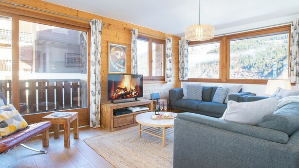 Een gezellige woonkamer met een open haard, een bank, een salontafel en een televisie.