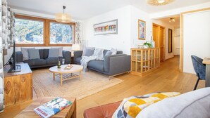 Een moderne woonkamer met een grijze bank, een salontafel en een houten kast.