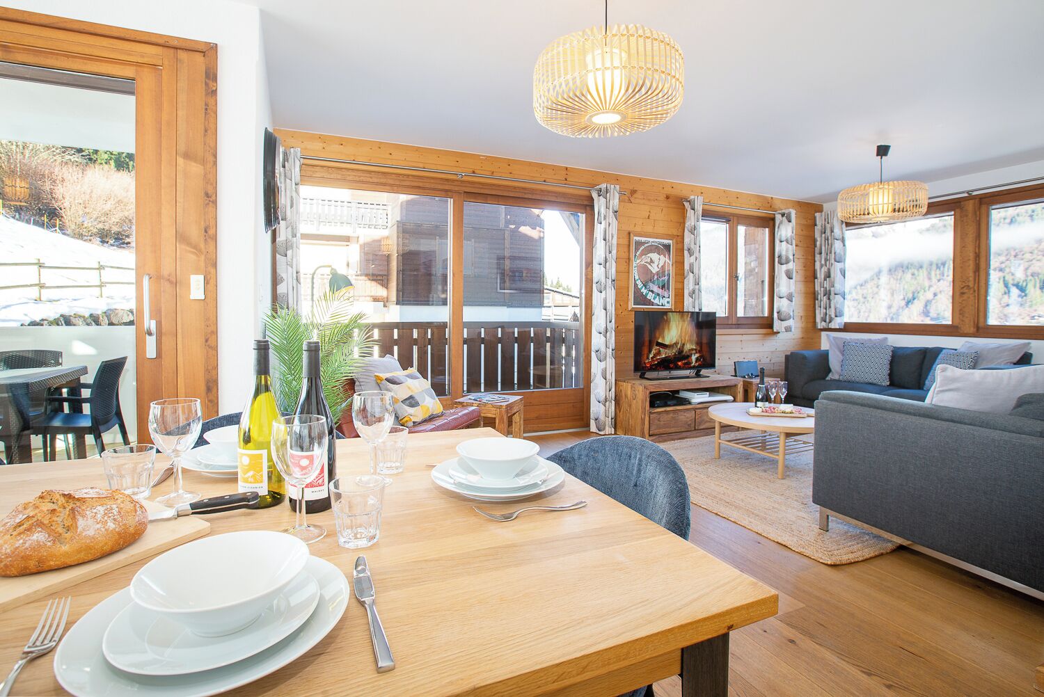 Ein gemütliches Wohnzimmer mit einem Holzesstisch für zwei Personen, einer Couch und einem Kamin.
