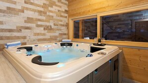 A hot tub with a wooden wall and window in the background. - The Crows Nest hosted by More Mountain, Morzine | Luxury 5 Bed 5 Bath Private Chalet | Sleeps 10.  Fantastic Central location in Morzine in the heart of the village. Family friendly with All Mod Cons. Only 5 mins walk to Ski Lifts. (Morzine)