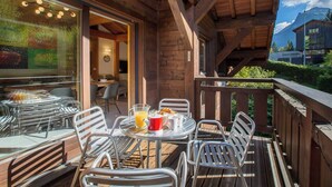Eine Holzterrasse mit Sitzgelegenheiten, einem Essbereich und Blick auf Berge.