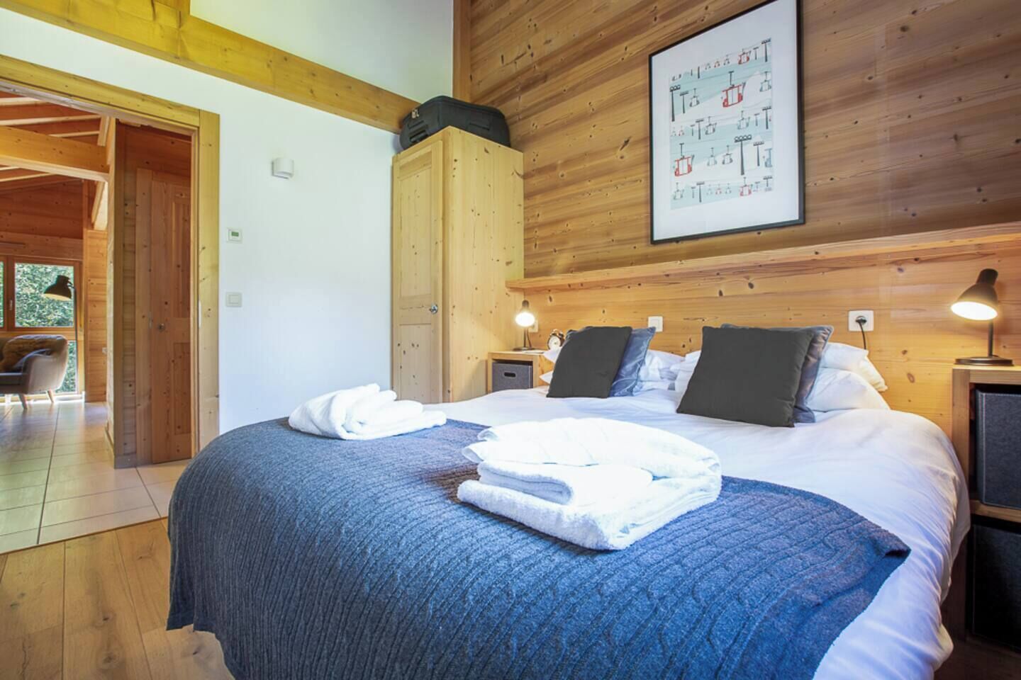 Een slaapkamer met een groot bed, houten wanden en een ingelijst schilderij aan de muur.