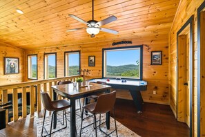 A wooden cabin with a pool table, chairs, and a ceiling fan. - Heavenly Daze (Sevierville)