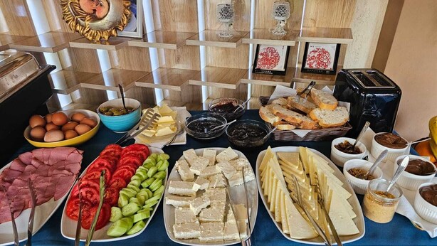 A buffet table with various food items including meats, cheeses, and bread. - Hotel Promenade (Shkodër)
