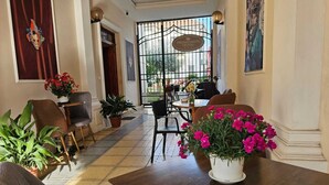 A hotel lobby with a tiled floor, a reception desk, and a dining area with chairs and tables. - Hotel Promenade (Shkodër)