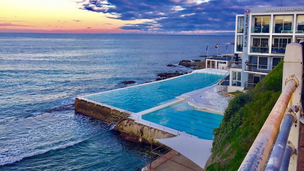 A coastal hotel with a pool overlooking the sea, a lifeguard tower, and a building labeled 'Surf Life Saving Australia.'