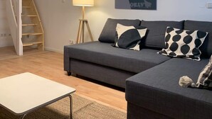 A living room with a grey sofa, a white coffee table, a lamp, and a painting on the wall.