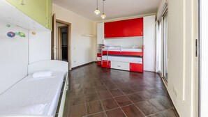 A room with a bunk bed, a desk, and a chair. There is a window with curtains, a door, and a light fixture on the ceiling. - Spacious Stay in the Heart of Tirana 2BR City View (Tirana)
