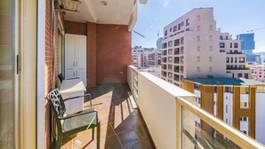 A balcony with a table and chairs, a white door, and a view of surrounding buildings. - Spacious Stay in the Heart of Tirana 2BR City View (Tirana)