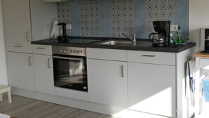 Una cocina moderna con horno empotrado, cafetera y lavamanos.
