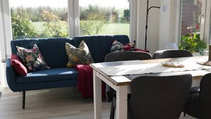 Una sala de estar moderna con un sofá azul, una mesa de comedor y sillas.