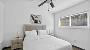 A bedroom with a bed, nightstands, a ceiling fan, a window with blinds, and a wall-mounted artwork. - Bright 2Bd 1Bt Homes in Central Wellington (College Park)
