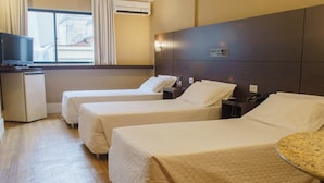 Habitación de hotel con dos camas, un escritorio pequeño con televisor y una ventana con cortinas.