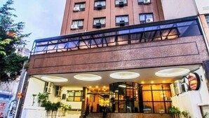 Un hotel con diseño moderno, que presenta fachada de ladrillo, entrada de vidrio y una escalera que conduce al vestíbulo.