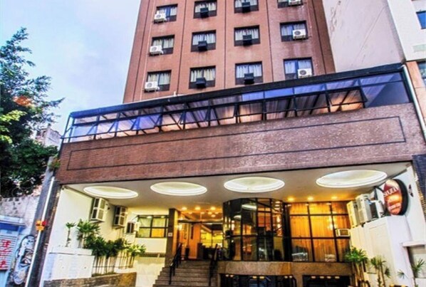A hotel with a modern design, featuring a brick facade, a glass entrance, and a staircase leading to the lobby.