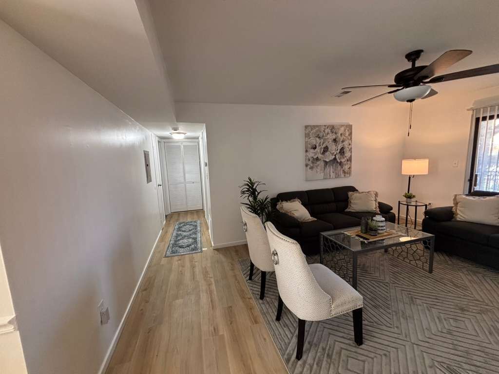 A living room with a sofa, chairs, a coffee table, and a ceiling fan.
