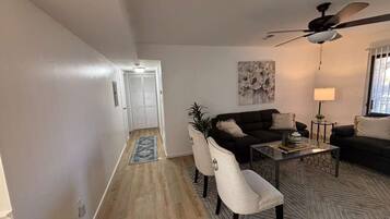 A living room with a sofa, chairs, a coffee table, and a ceiling fan.