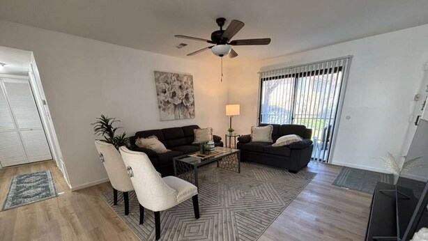Un salon avec un ventilateur de plafond, deux canapés, une table basse et un tapis.