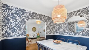 Ein Essbereich mit Tisch, Stühlen und einer Wand mit Blattmotiven.