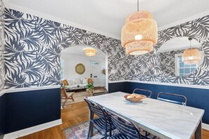 Zona pranzo con tavolo, sedie e parete decorata con motivi a foglia.