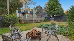 A backyard with a deck, outdoor seating, and a fire pit.
